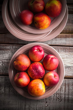 Peaches overhead colorful group on pale red plates and white old rustic wooden table in studio