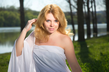 Naklejka premium Beautiful blonde girl on the river bank.