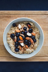 bowl of healthy oatmeal with fruit and nuts on wood surface