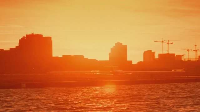 London City Airport - A wide angle environment shot of an airliner landing during sunset. London City Airport opened in 1987 and serves the twin centers of London's financial industry.
