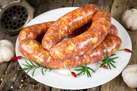 Raw sausages with rosemary and chili peppers on the plate