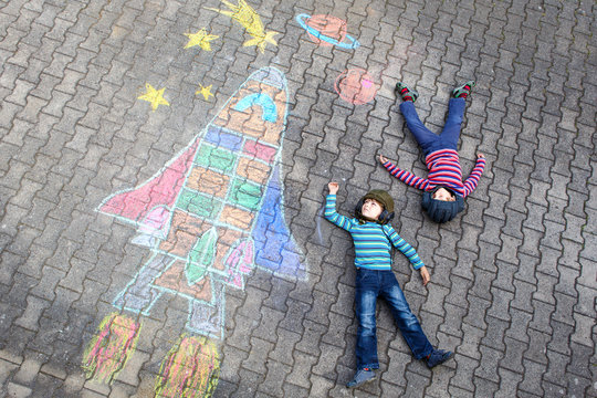 Two little kid boys flying by a space shuttle chalks picture
