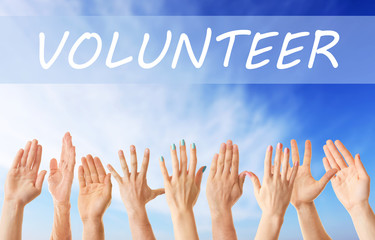 Hands and word VOLUNTEER on blue sky background. Help and support concept.