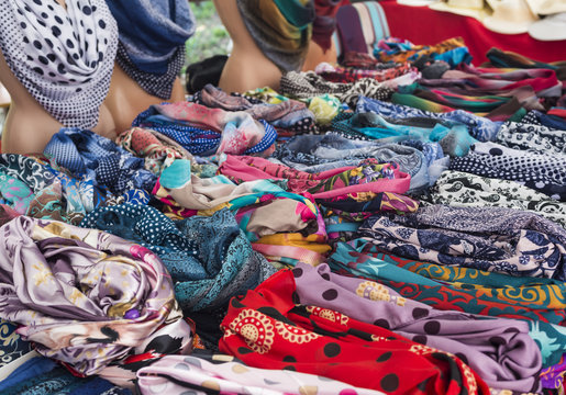 Rows of colorful silk scarves lie on a market stall