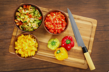 Bowls with fresh chopped pepper on cutting board, top view