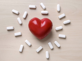 Red heart with pills on table