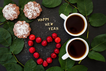 inscription of new year on a black board with cupcake and heart in the form cherries