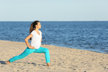 Fototapeta na wymiar Young pregnant woman doing yoga exercises on the beach