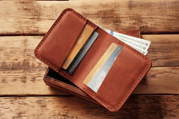 Stylish leather wallet with money and box on wooden background