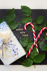 inscription of new year on a black board with  nice gift and red candy