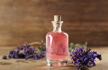 Obraz na płótnie Canvas Bottle with aroma oil and lavender flowers on wooden background