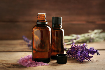 Bottle with aroma oil, sea salt and lavender flowers on wooden background