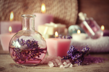 Obraz na płótnie Canvas Spa concept. Bottle with lavender aroma oil and candles on wooden background