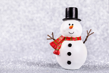 Snowman toy on shiny silver background