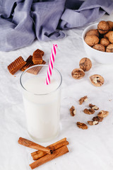 fresh healthy milk, walnuts, toffee, cinnamon sticks on white background. selective focus.