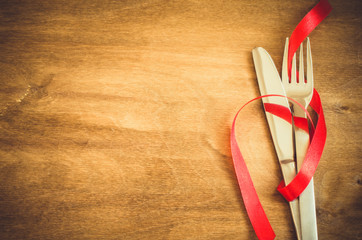 Silverware Decorated with Red Ribbon on Wooden Background.