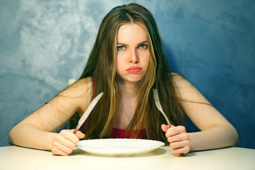 Hungry young woman waiting with an empty plate.