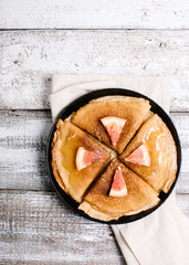 Pancake in a frying pan on a wooden background, minimalism in serving, top view