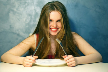 Hungry young woman waiting with an empty plate.