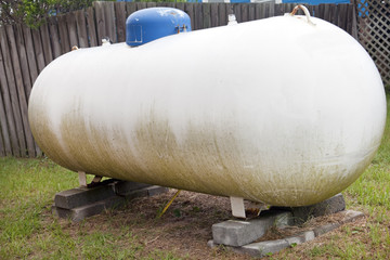 Dirty propane tank with blue cap. Horizontal.