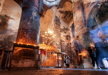 Fototapeta premium People praying with candles in dark interior of Church of the Archangels with frescoes