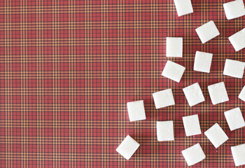 White sugar cubes on red squared background. Copy space. Top view