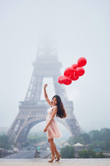 Parisian woman with red balloons in front of the Eiffel tower
