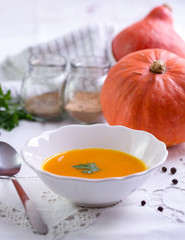 Autumn pumpkin soup on white tablecloth.