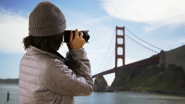 Pretty photographer taking pictures of golden gate bridge in San Francisco.