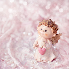 Angel toy with a heart in hand on a Christmas background .Christmas card. Christmas decoration.