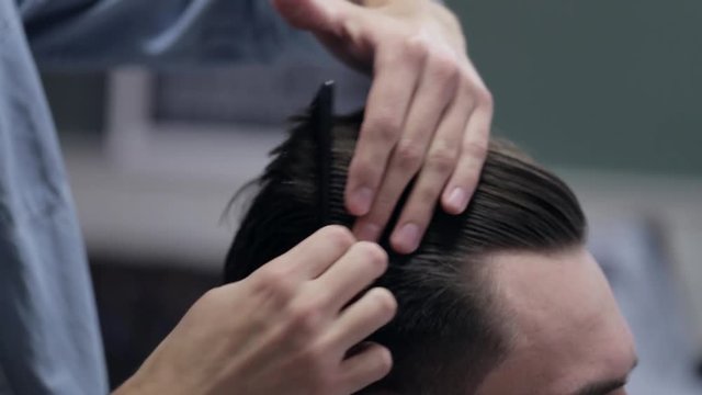 Barber adding some wax and combing client.