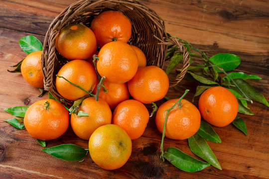 Tangerines basket scattered fruits on woden table