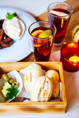 Buns with caraway seeds in a wooden bowl with olives and butter.