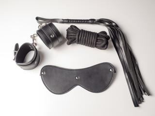 Leather handcuffs, leather whip and leather mask on white background. BDSM Kit