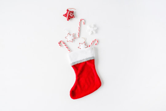 Creative Arrangement Of Bright Red Christmas Toys In Christmas Sock On White Background. Flat Lay, Top View