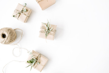 creative arrangement pattern of craft boxes and green branches on white background. flat lay, top view