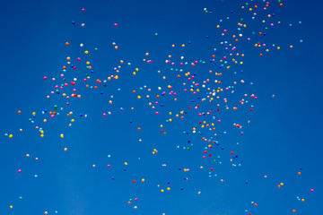 Hundreds of colorful ballons are flying through the blue cloudless sky