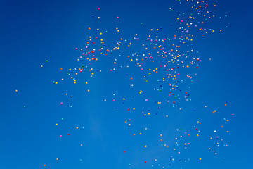 Hundreds of colorful ballons are flying through the blue cloudless sky