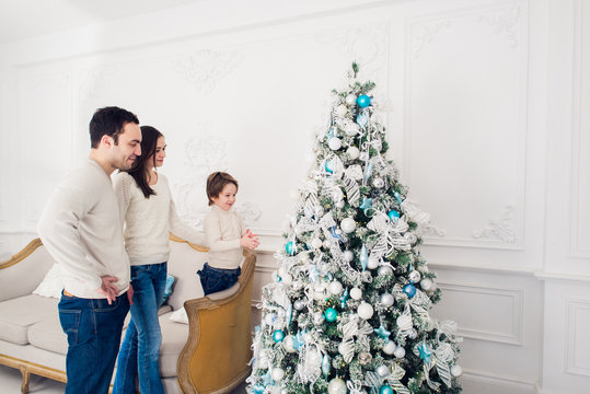 Family decorating a Christmas tree with boubles in the living-room