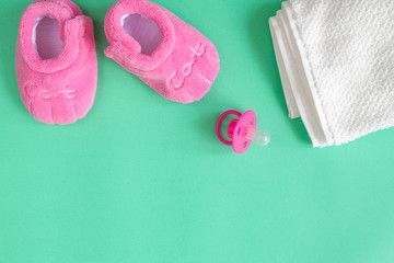 children's clothes and baby booties on green background