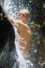 Man taking a relaxing shower under waterfall. outside