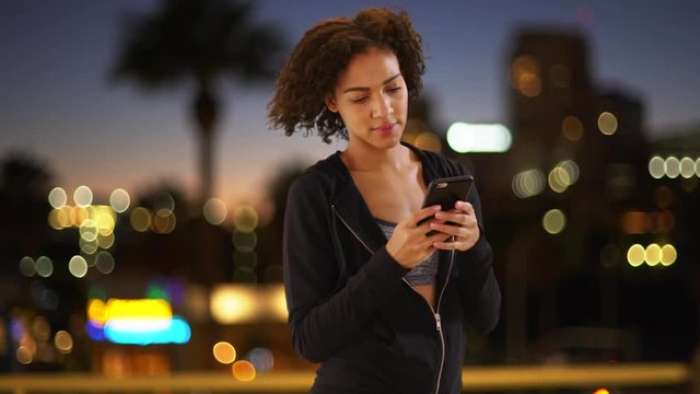 Lovely black woman using smartphone in urban setting.