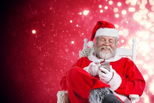 Composite image of happy santa claus messaging with mobile phone