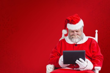 Composite image of santa claus looking at digital tablet