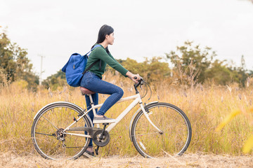Fototapeta na wymiar Teenager girl, bicycle with flowers basket in outdoor landscape