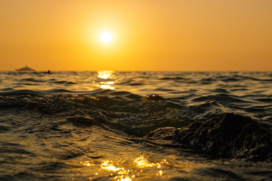 Sea Wave Close Up At Sunset Time With Red And Orange Sun Reflection On The Water. Nature Abstract Blurred Background. Phuket Island, Thailand