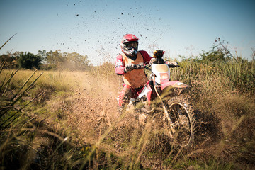 Off road dirt bike rider splashing mud in hard enduro rally race