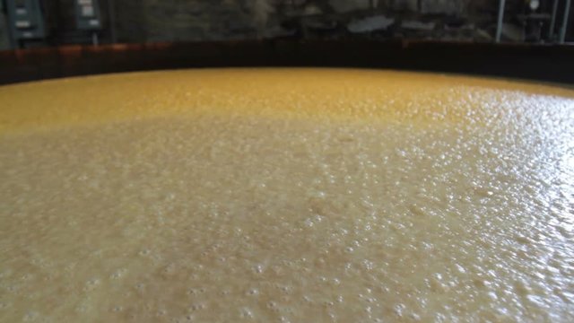 Wooden vat with fermenting corn mash inside stone bourbon distillery in Kentucky.