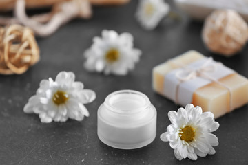 Fototapeta na wymiar Soap, cream and daisy flowers on grey table
