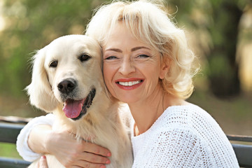 Senior woman sitting on bench with dog, closeup